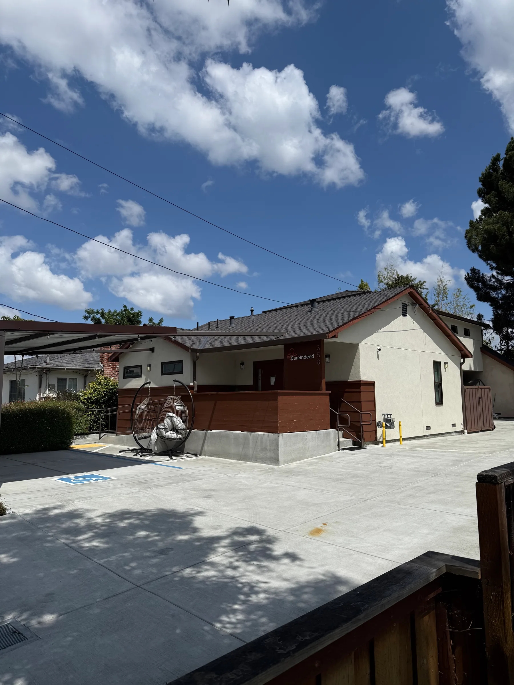 Care facility exterior with wood-clad walls, an accessible ramp, and a new concrete parking area