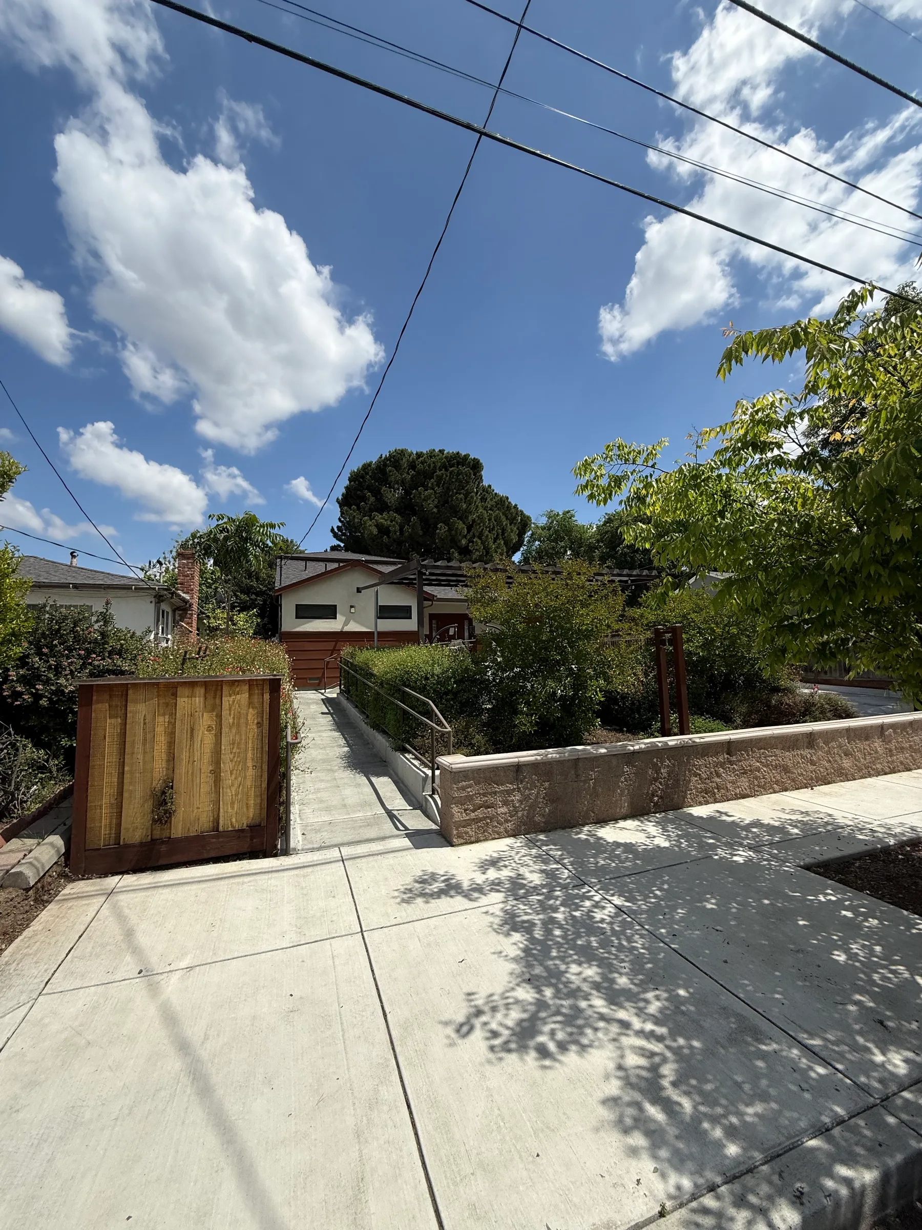New concrete walkway and low retaining wall with a redwood gate alongside a home