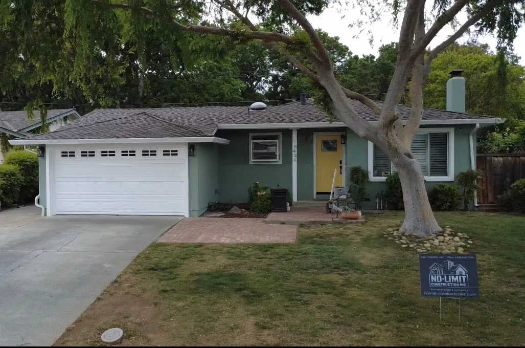Repainted ranch home with a yellow front door, white garage door, and stamped brick walkway