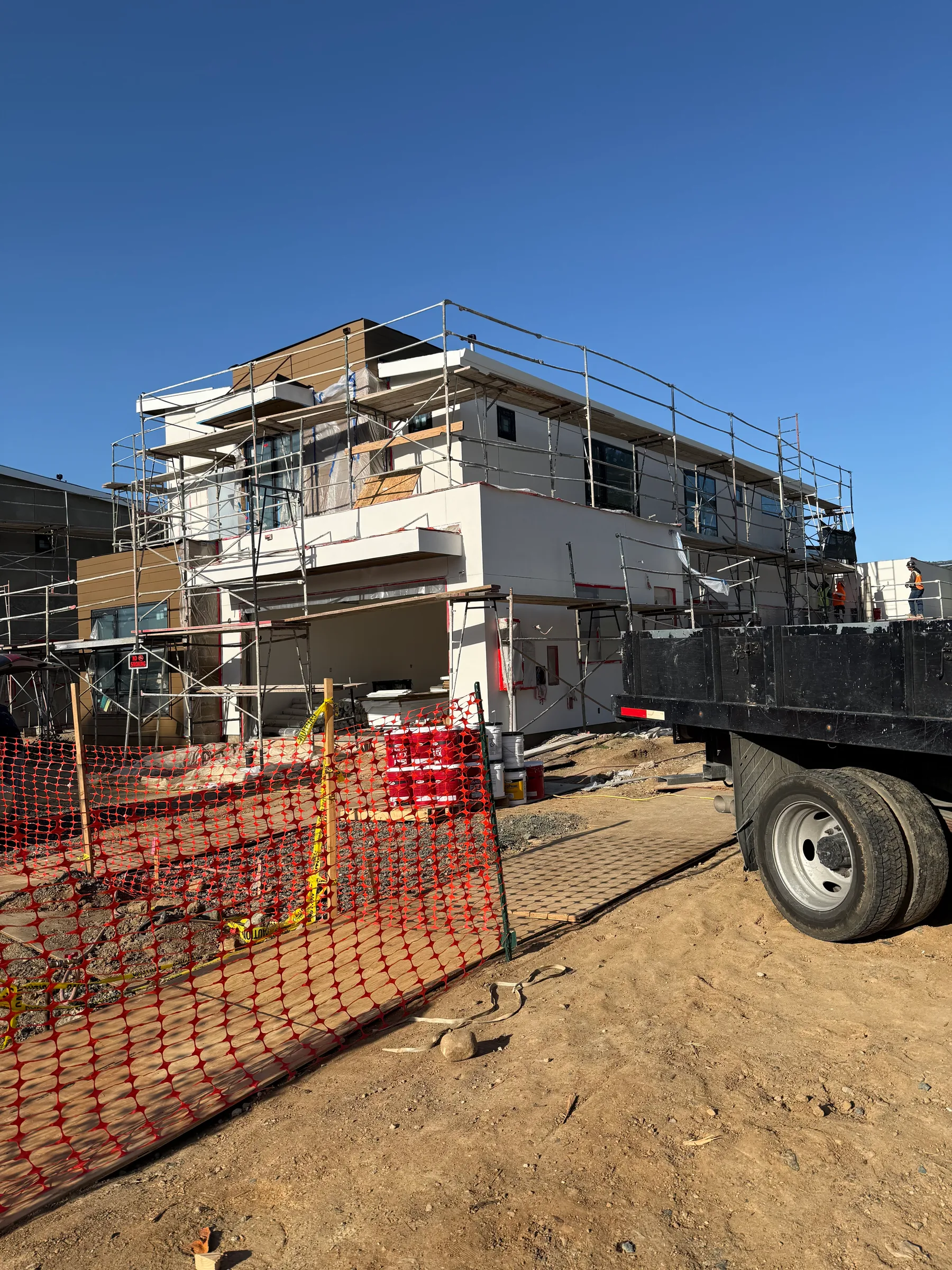 Multi-story building mid-construction with scaffolding and exterior stucco work underway