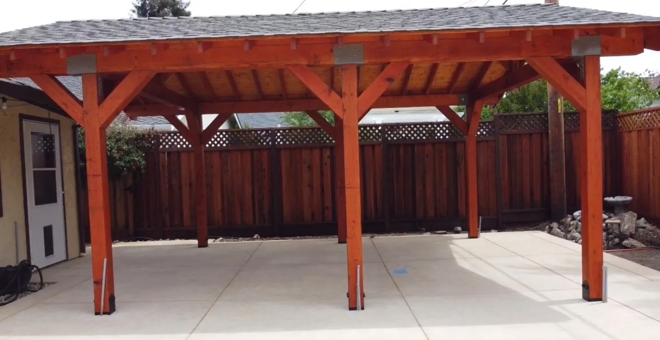 Freestanding redwood patio cover over a broom-finish concrete slab beside a new lattice-top fence