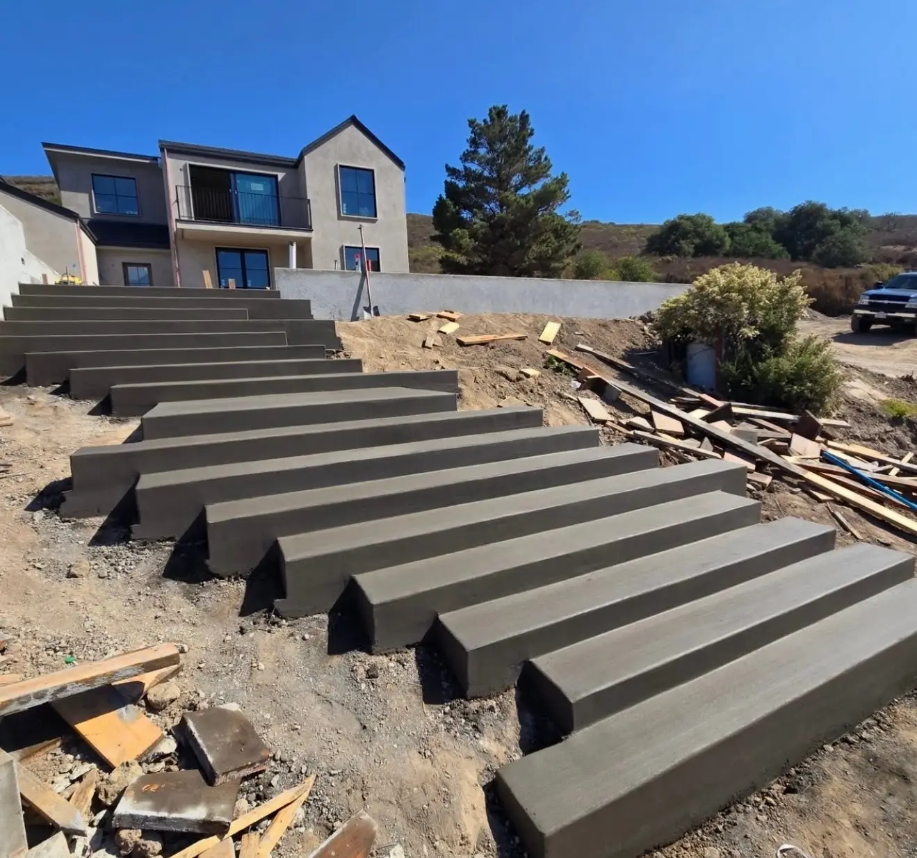 Wide cast-in-place concrete steps climbing a hillside lot to a new two-story home