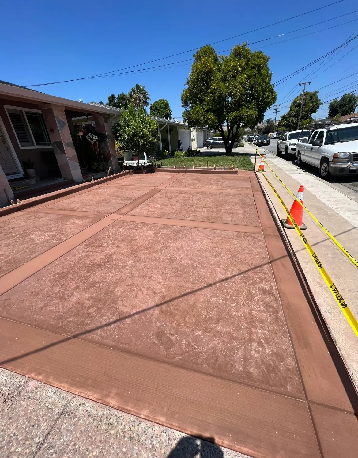 Terracotta stained concrete driveway with saw-cut panels and a darker perimeter border at the street