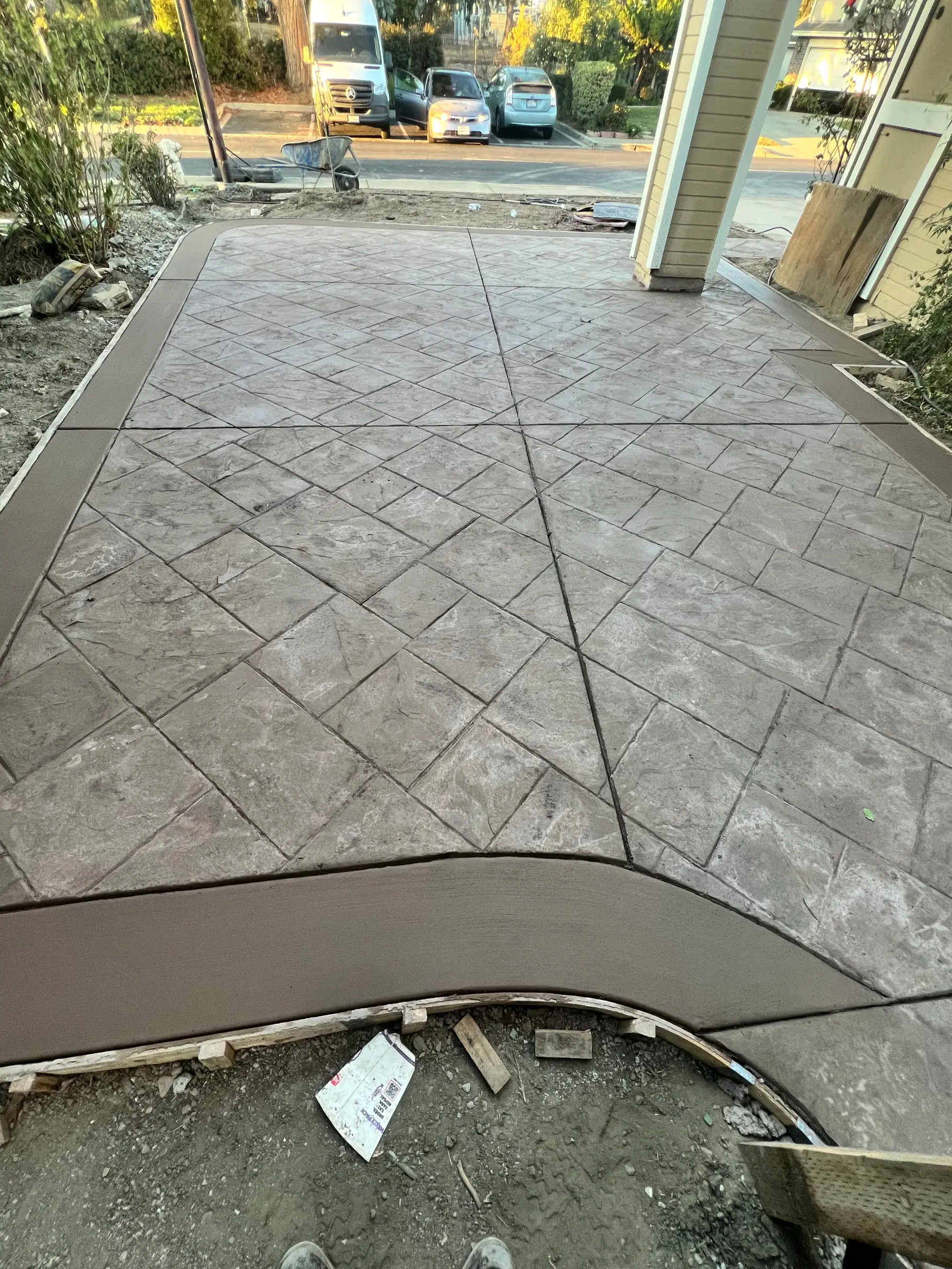 Stamped concrete driveway in a gray ashlar slate pattern with a curved contrasting brown border