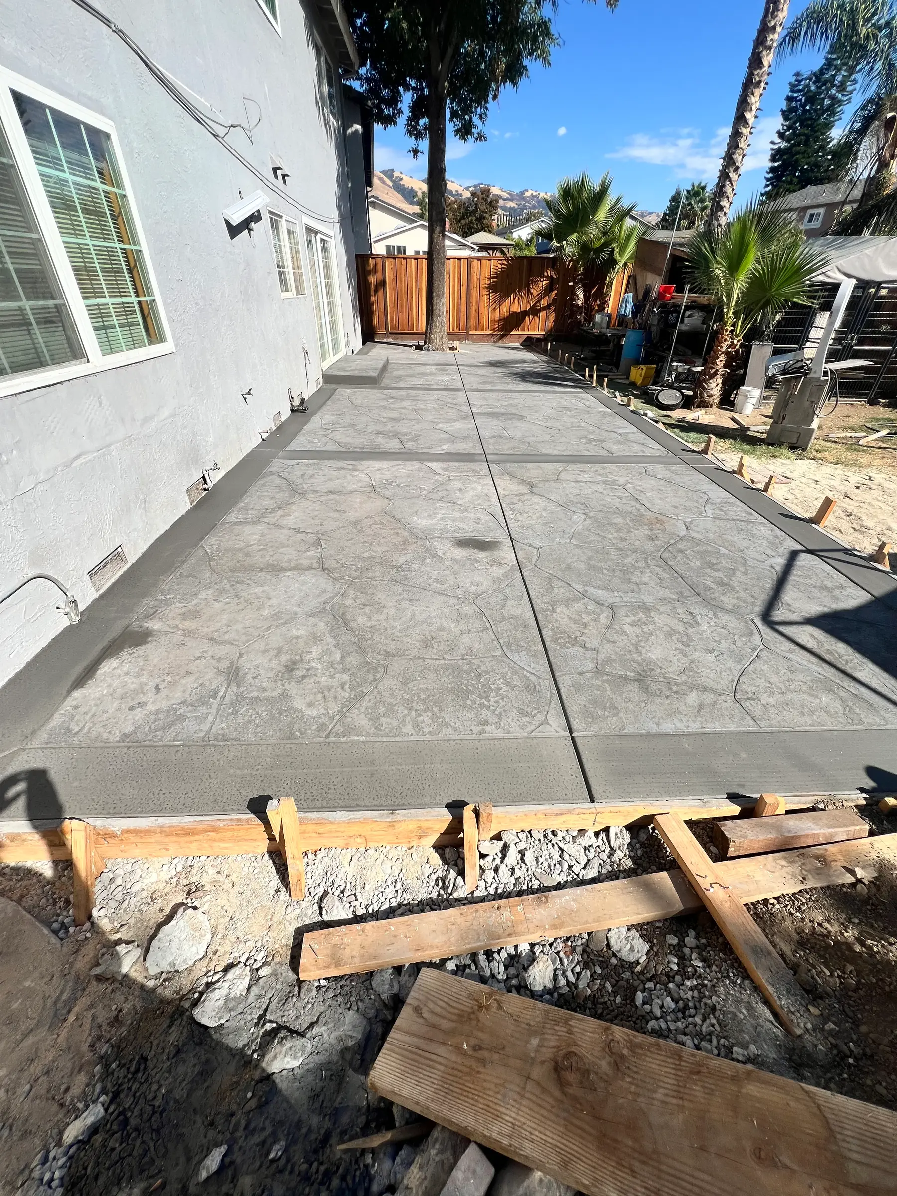 Freshly finished stamped concrete side patio with the wood forms still set along the edge
