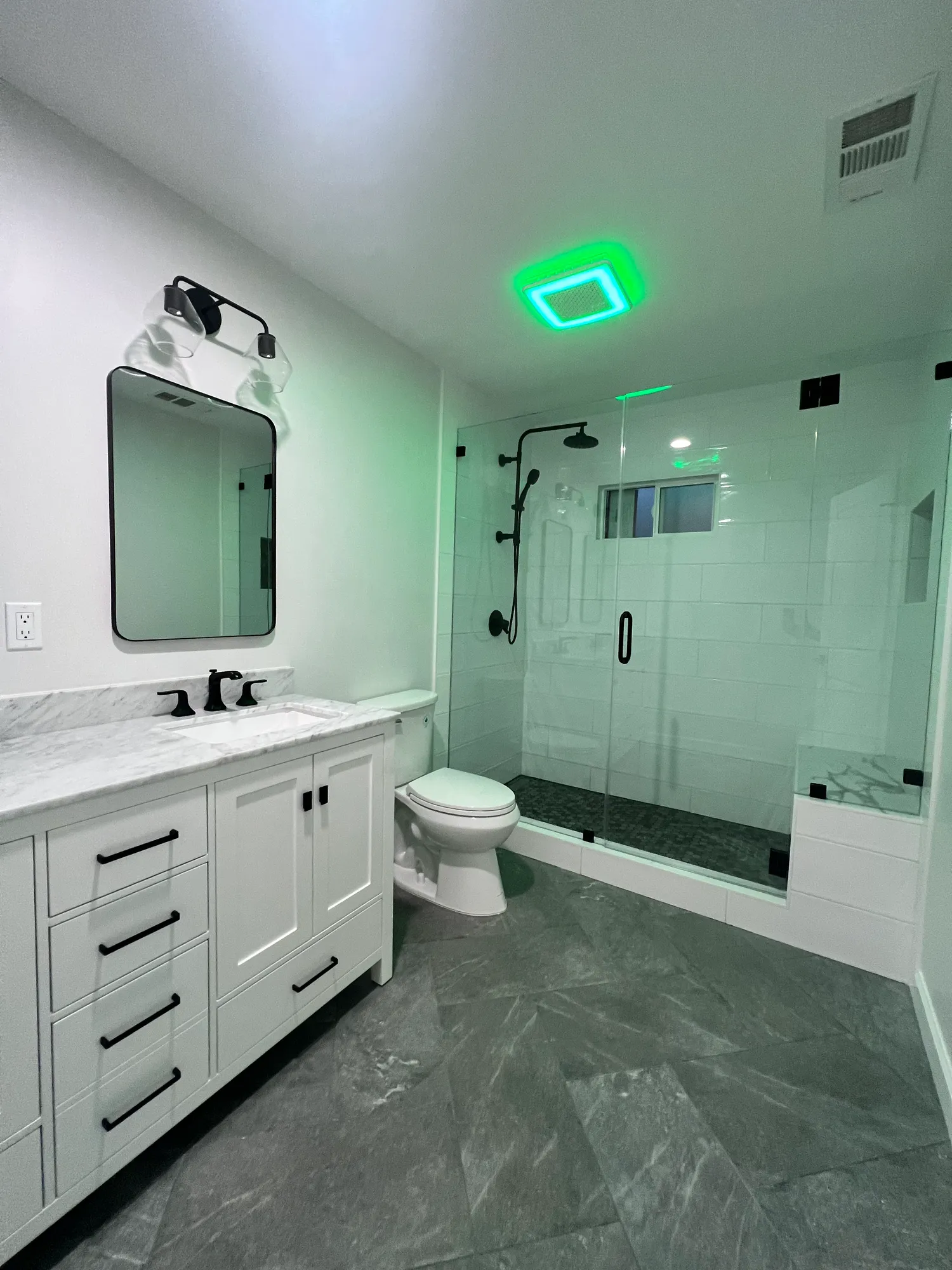 Bathroom remodel with a white shaker vanity, marble countertop, and a frameless glass walk-in shower