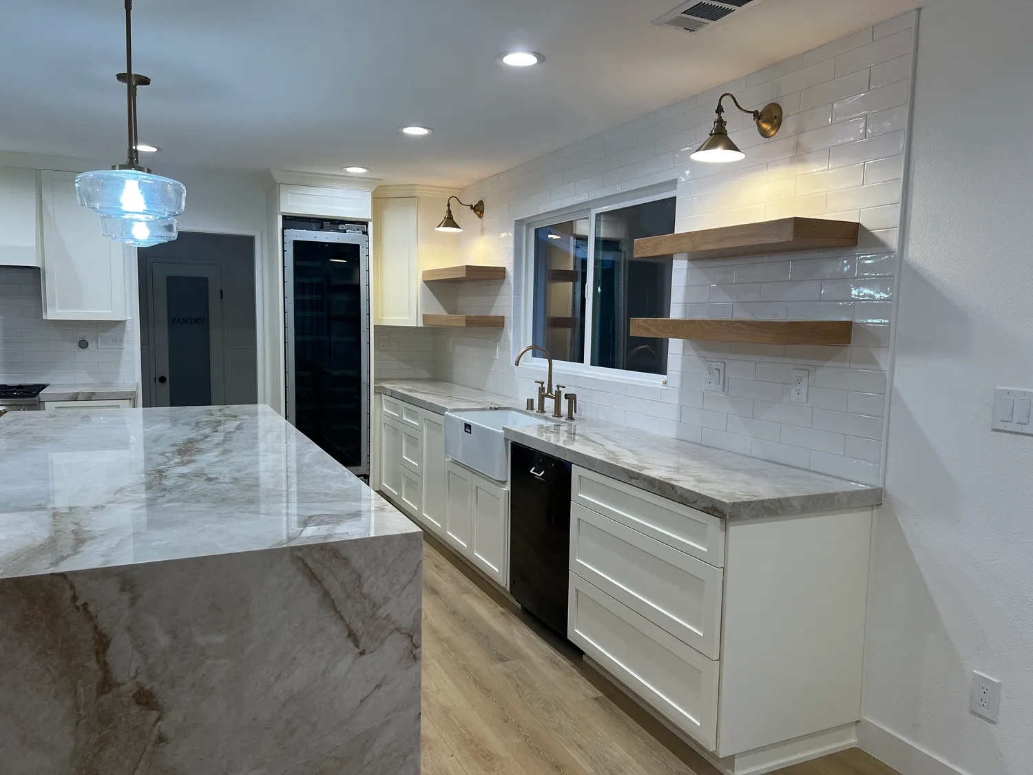 Kitchen remodel with white shaker cabinets, a quartzite island, farmhouse sink, and floating oak shelves