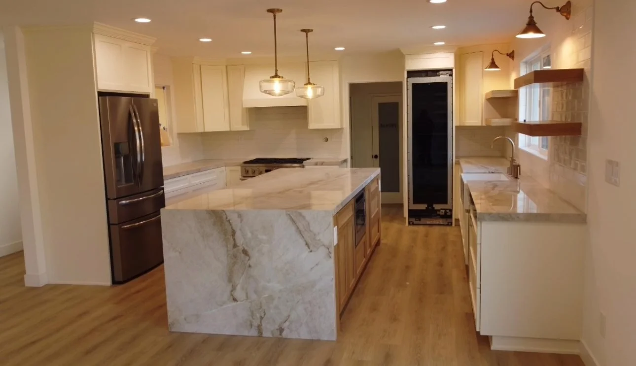 Open kitchen remodel with white cabinetry, marble waterfall island, and pendant lighting