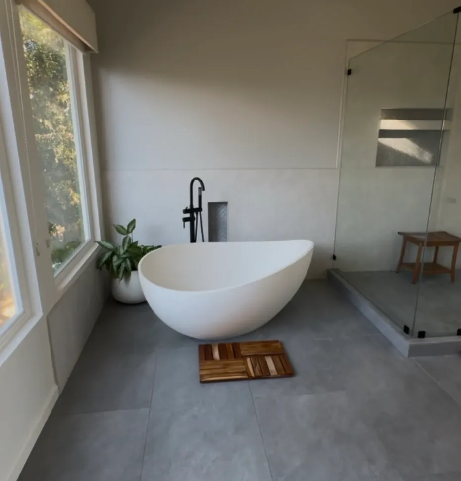 Primary bathroom with a freestanding soaking tub, matte black floor filler, and a glass shower with teak bench