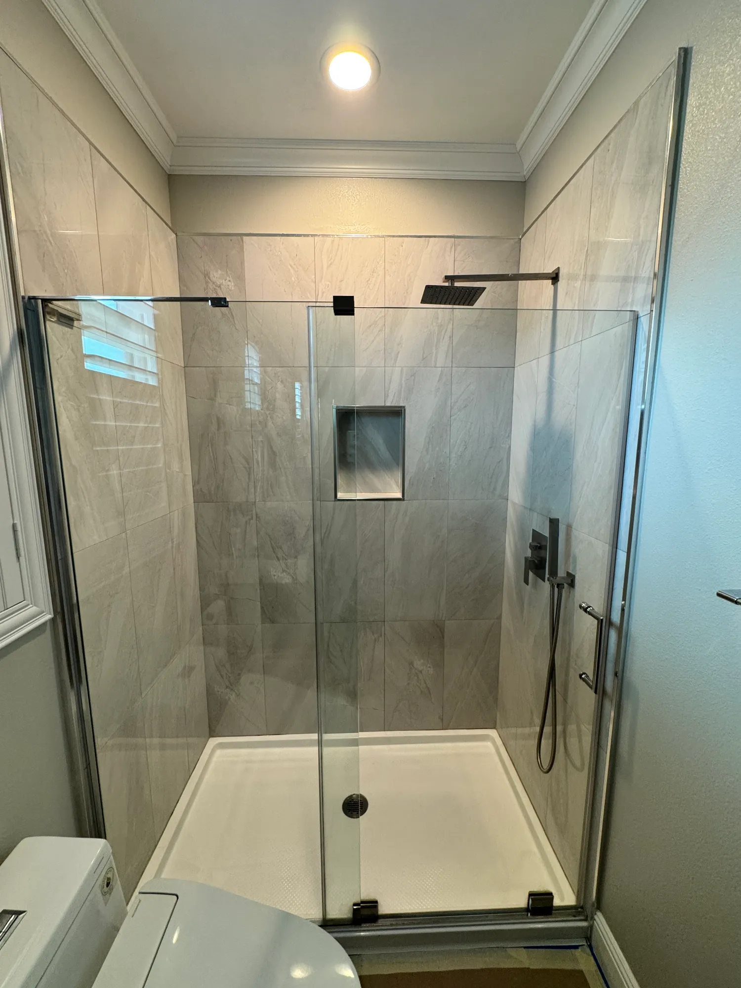 Shower remodel with large-format porcelain wall tile, a recessed niche, and a frameless glass enclosure