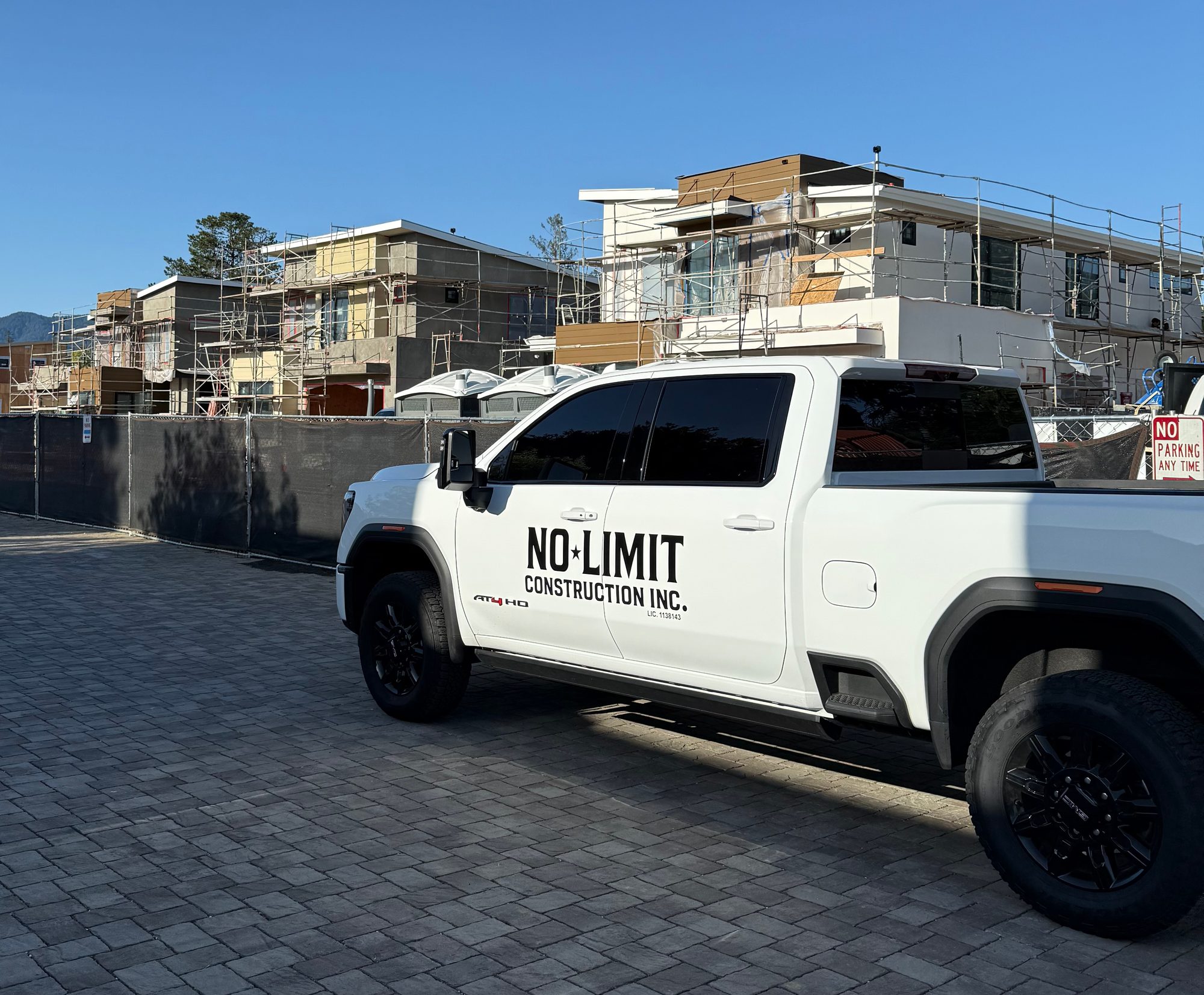No Limit Construction truck parked at a Bay Area multifamily project under scaffolding