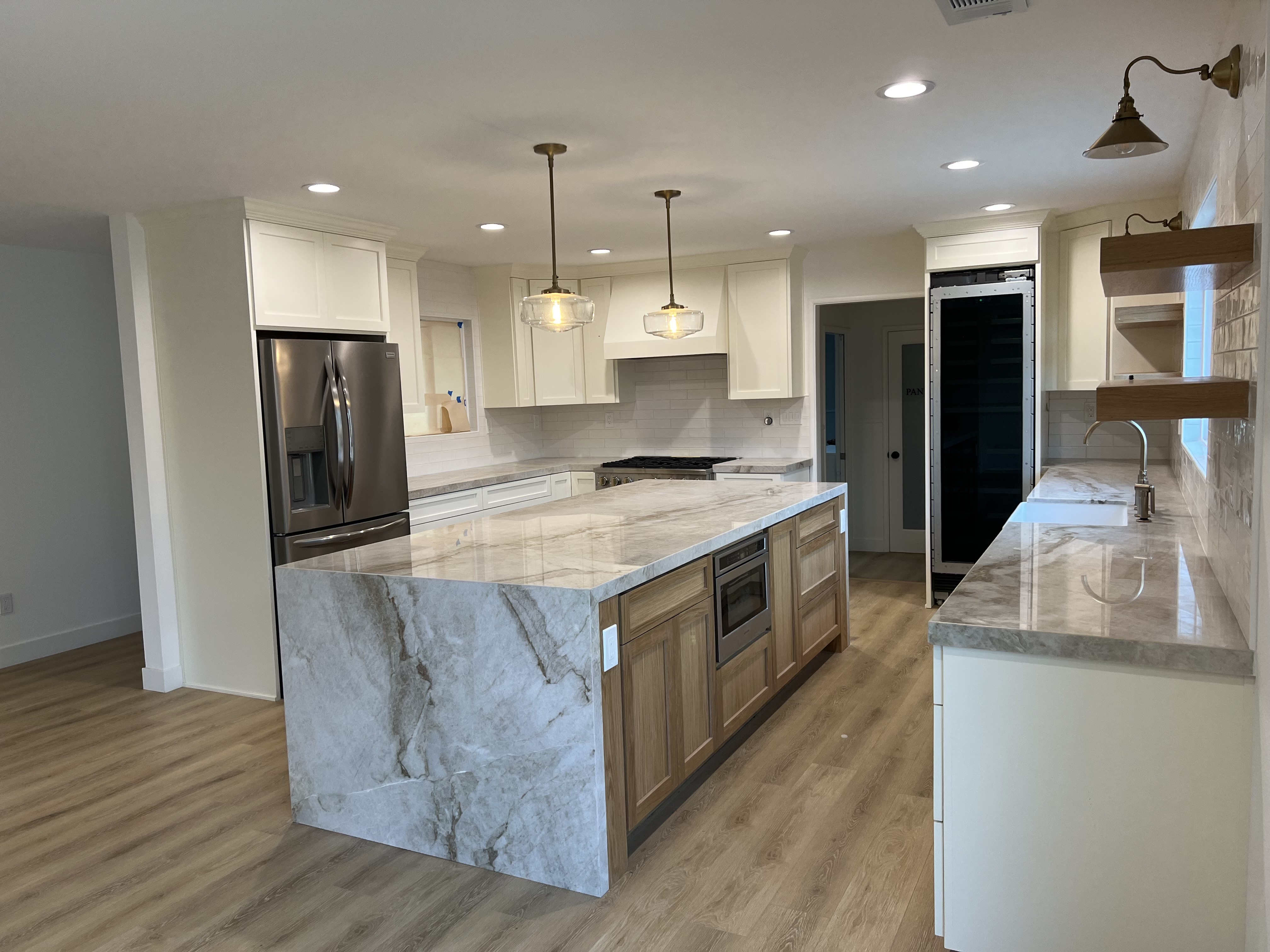 Remodeled kitchen with marble island, custom cabinetry, and pendant lighting by No Limit Construction.